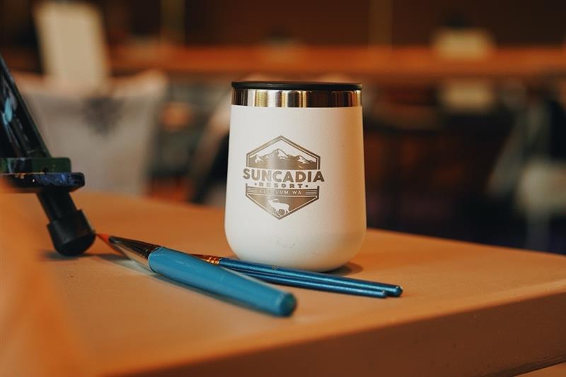 White Suncadia Resort tumbler with two paintbrushes on a table.