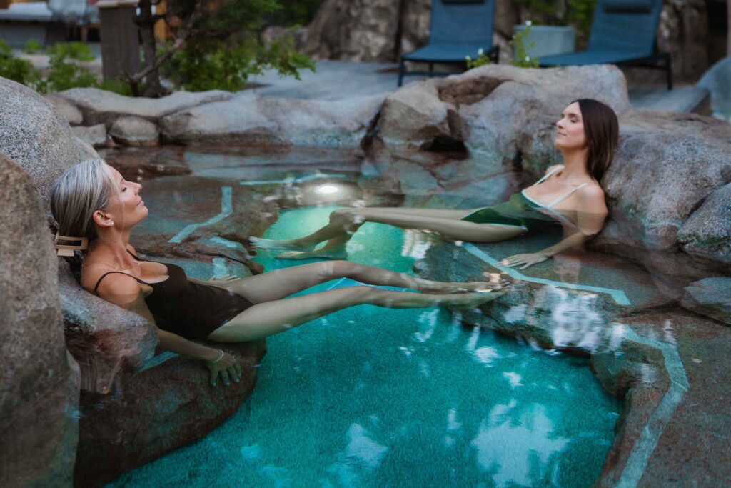 Two women relaxing in a natural rock hot spring.